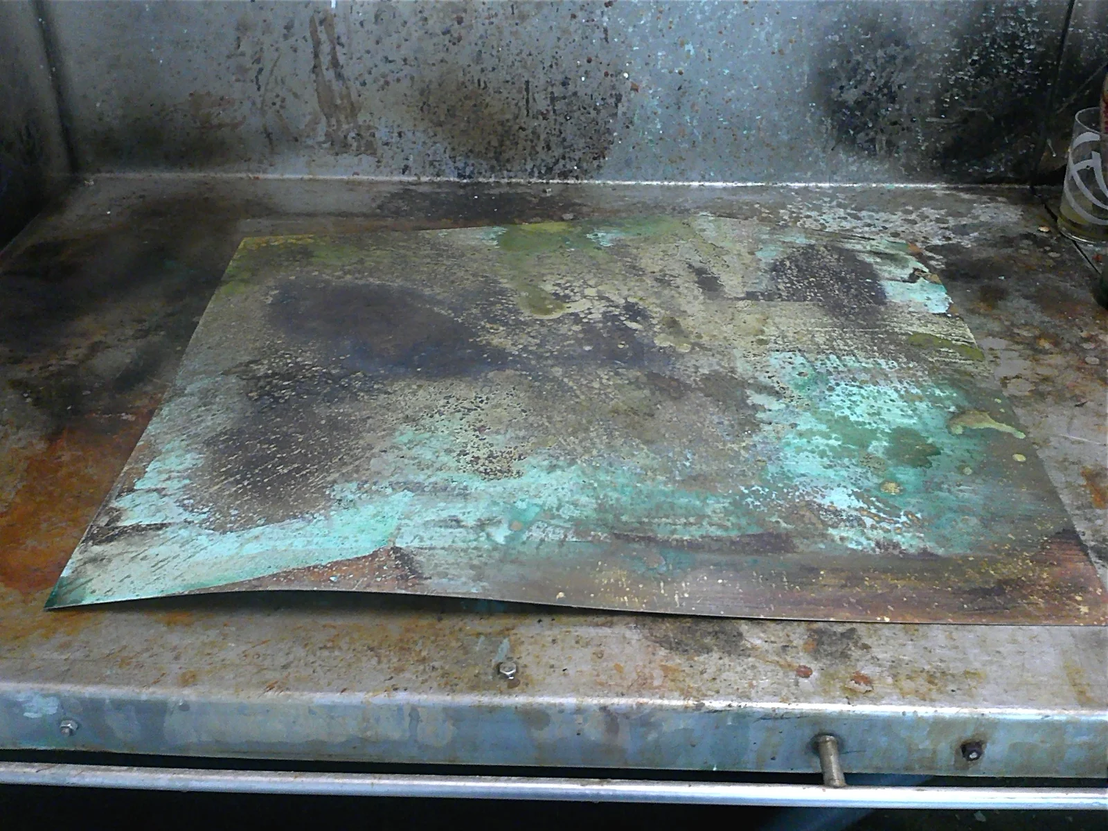 Plancha de latón durante el proceso de patinado