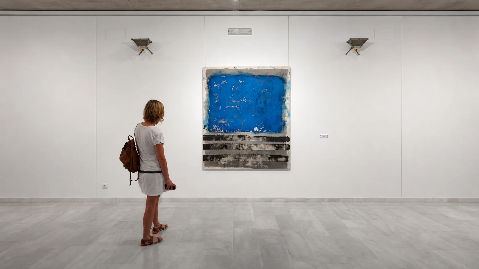 Visitante ante una obra azul y gris de Mar Ortega